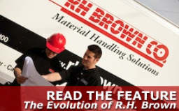 Worker wearing red hard hat and holding a large technical drawing while another worker points at the drawing. Clickable Image says, Read the Feature: The Evolution of RH Brown.