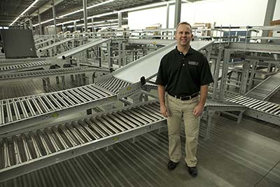 Scott Larsen with a conveyor system in the background